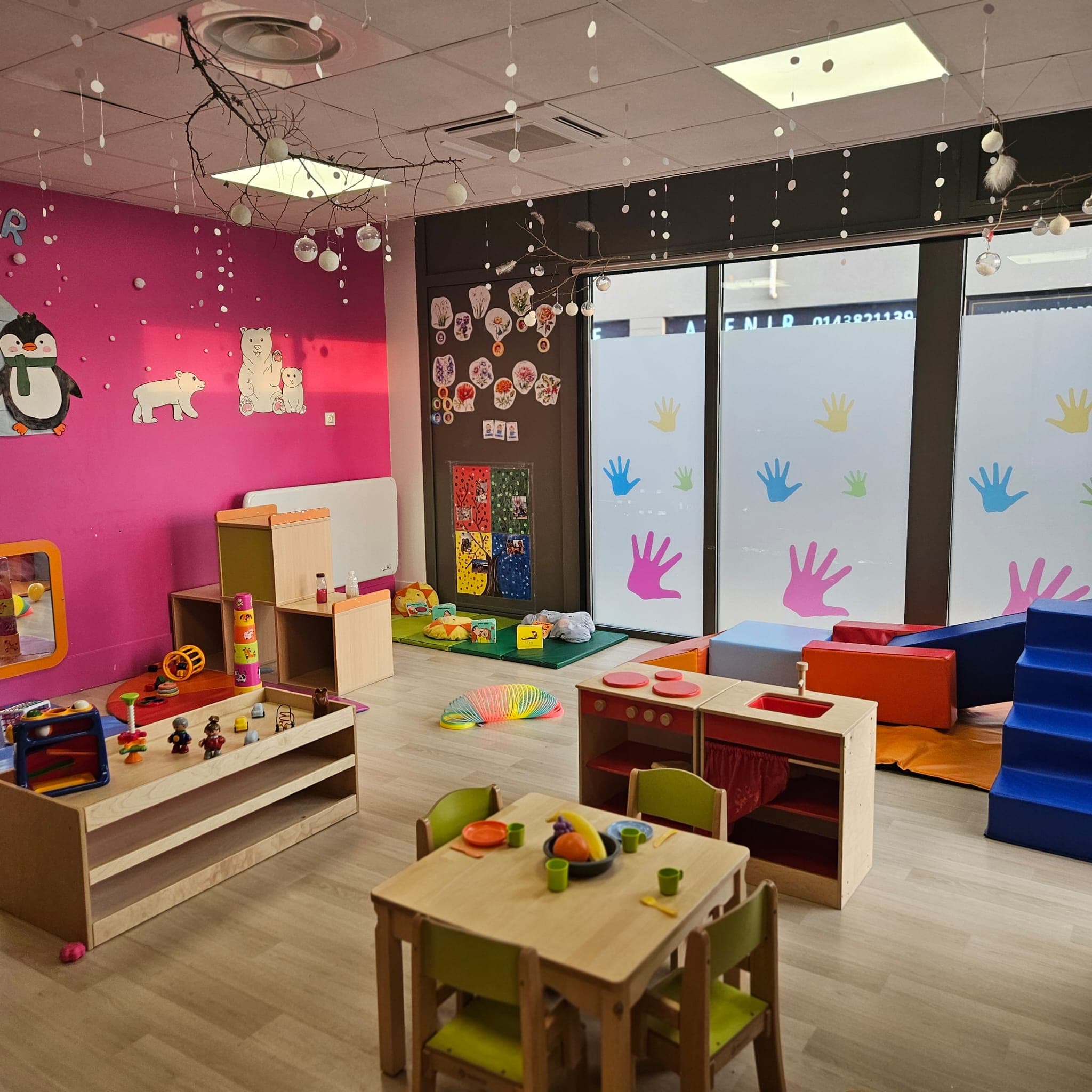 Salle principale avec mur fuchsia, jouets et mobilier coloré
